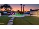 Beautiful backyard with a sparkling pool, a hot tub, lush landscaping, and colorful decorative lighting at 14012 N 57Th Pl, Scottsdale, AZ 85254