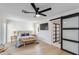 Serene bedroom featuring a tufted headboard, a sliding barn door to the bathroom and a ceiling fan at 14012 N 57Th Pl, Scottsdale, AZ 85254