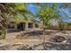 View of the rear of the home revealing a covered patio, desert landscaping, mature trees, and a brick privacy wall at 1641 W Windsong Dr, Phoenix, AZ 85045
