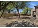 View of a yard showcasing desert landscaping, gravel, mature trees, and a brick privacy wall at 1641 W Windsong Dr, Phoenix, AZ 85045