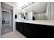 Bathroom features a dark vanity, mirror, and a walk-in shower with glass doors at 17426 W Calavar Rd, Surprise, AZ 85388