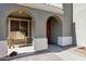Inviting front porch with a cozy wooden bench and an arched entryway at 17426 W Calavar Rd, Surprise, AZ 85388