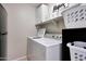 Bright laundry area with white washer and dryer, storage cabinets, and charming decorative accents on shelves at 17426 W Calavar Rd, Surprise, AZ 85388