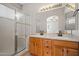 Bathroom with a double vanity, wood cabinets, a large mirror, and a glass-enclosed shower at 17805 W Arizona Dr, Surprise, AZ 85374