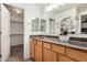 A wooden vanity with stone countertop and dual mirrors, enhances this bathroom, which features a walk-in closet at 17862 N 114Th Ln, Surprise, AZ 85378