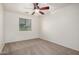 An empty bedroom, featuring neutral colored walls, carpeting, ceiling fan, and a window with a view of the outdoors at 17862 N 114Th Ln, Surprise, AZ 85378