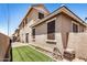 A view of the side of the house with synthetic grass and paver patio at 17862 N 114Th Ln, Surprise, AZ 85378
