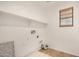 A bright laundry room with white walls, shelving, and hookups, illuminated by natural light from a window at 17862 N 114Th Ln, Surprise, AZ 85378