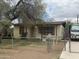 Cozy single-story home featuring a large front tree and partially fenced yard at 2415 E Wood St, Phoenix, AZ 85040