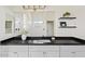 Bathroom with white cabinets, black countertop, dual sinks, and decorative floating shelves at 2421 S 65Th Dr, Phoenix, AZ 85043