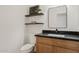 Stylish powder room with wood vanity, black countertop, modern fixtures, and floating shelves at 2421 S 65Th Dr, Phoenix, AZ 85043