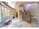 Bright foyer featuring travertine floors, a curved staircase with iron railing, and a comfortable sitting area at 3804 E Camelback Rd, Phoenix, AZ 85018