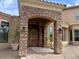 Inviting front entrance with stone columns, a wooden arched door, lanterns, and a brick pathway at 3804 E Camelback Rd, Phoenix, AZ 85018