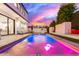 Backyard pool with blue and pink lights, with easy access to a custom kitchen and a spacious lounging area at 4131 E Roma Ave, Phoenix, AZ 85018