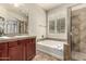 Bright bathroom featuring a double sink vanity, soaking tub, and a glass-enclosed shower at 418 W Balsam Dr, Chandler, AZ 85248