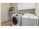 A convenient laundry room with a front load washer and dryer and cabinet storage at 418 W Balsam Dr, Chandler, AZ 85248