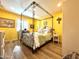 Bright bedroom with a wooden floor and a four-poster bed beneath a ceiling fan and yellow colored walls at 4554 E Paradise Village N Pkwy # 133, Phoenix, AZ 85032