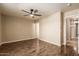 Bright bedroom with hardwood flooring, ceiling fan, neutral paint, and doors leading to an ensuite bathroom at 4731 N 86Th Dr, Phoenix, AZ 85037