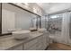 Bathroom with dual vessel sinks, granite countertop, decorative lighting, and a shower with marble tiles at 4812 W Butler Dr, Chandler, AZ 85226