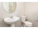 Powder room with pedestal sink, round mirror, and toilet at 503 N Ranger Trl, Gilbert, AZ 85234