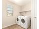 Bright laundry room featuring a front-loading washer and dryer, and a shelf for organizing laundry supplies at 503 N Ranger Trl, Gilbert, AZ 85234