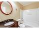 A simple bathroom featuring a round mirror, dark vanity, and a combined shower and bathtub at 5734 S 21St Pl, Phoenix, AZ 85040
