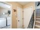 Hallway with utility closet, access to laundry room with washer and dryer, leading to carpeted stairs at 5734 S 21St Pl, Phoenix, AZ 85040
