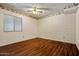 A bedroom featuring a wood floor, window, ceiling fan, and light floral wallpaper at 6015 W Acoma Dr, Glendale, AZ 85306