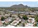 Aerial view featuring red-tiled roofs in a community with mountain views and commercial buildings in the background at 7319 E Rose Ln, Scottsdale, AZ 85250