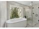 Bright bathroom featuring a soaking tub and glass shower with nature views at 7319 E Rose Ln, Scottsdale, AZ 85250