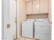 Laundry room has white washer and dryer, storage cabinets, and a tile floor at 8566 N 108Th Ln, Peoria, AZ 85345