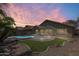 Back yard with a covered patio and a sparkling blue swimming pool at sunset at 1037 E Baylor Ln, Gilbert, AZ 85296