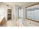 Bright bathroom featuring a soaking tub, glass-enclosed shower, and tile flooring at 1037 E Baylor Ln, Gilbert, AZ 85296