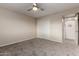 Bright bedroom with neutral carpet, ceiling fan, closet, and entry to hallway at 10516 W Peoria Ave, Sun City, AZ 85351