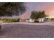 Spacious front yard with mature trees, gravel landscaping, and a well-maintained home exterior at 10516 W Peoria Ave, Sun City, AZ 85351