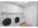 Bright laundry room features white cabinets and counter space, with modern washer and dryer at 14981 W Robson N Cir, Goodyear, AZ 85395