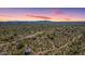 Expansive aerial view of a desert landscape with scattered vegetation and distant mountain range under a sunset sky at 18375 E San Ignacio Ct, Gold Canyon, AZ 85118