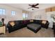 Bright living room with a black leather sofa, carpeted floor, ceiling fan and large windows at 18375 E San Ignacio Ct, Gold Canyon, AZ 85118
