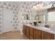 Bathroom featuring double sinks, white cabinets and patterned wallpaper at 18375 E San Ignacio Ct, Gold Canyon, AZ 85118