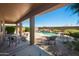 Covered patio with comfortable seating overlooks the sparkling pool and landscaped backyard at 18375 E San Ignacio Ct, Gold Canyon, AZ 85118