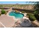 Inviting backyard oasis with a sparkling pool, waterfall feature, spa and desert landscaping in the background at 18375 E San Ignacio Ct, Gold Canyon, AZ 85118