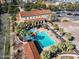 High angle view of a swimming pool with lounge chairs and palm trees with red tiled buildings in the background at 20518 W White Rock Rd, Buckeye, AZ 85396