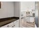View into a white kitchen with an island and dark countertops, with a peek at the living area at 20518 W White Rock Rd, Buckeye, AZ 85396
