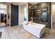 Bright bathroom showcasing a soaking tub, sliding barn door, and a glass-enclosed walk-in shower with dark accents at 22837 E Orchard Ln, Queen Creek, AZ 85142