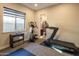 Bright home gym with a treadmill, elliptical machine, and a view into an adjacent bathroom at 22837 E Orchard Ln, Queen Creek, AZ 85142