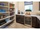 Walk-in pantry with custom shelving, granite countertops, beverage fridge and natural light at 22837 E Orchard Ln, Queen Creek, AZ 85142