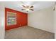 Bedroom with red accent wall, carpet floor, ceiling fan, and window at 2511 W Blue Sky Dr, Phoenix, AZ 85085