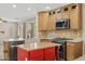 Well-appointed kitchen featuring light wood cabinets, island, farm sink and modern appliances at 2511 W Blue Sky Dr, Phoenix, AZ 85085