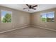 Bedroom with carpet flooring, ceiling fan, and two large windows at 2614 E Carob Dr, Gilbert, AZ 85298
