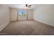 Expansive carpeted bedroom featuring a ceiling fan and a bright window at 2614 E Carob Dr, Gilbert, AZ 85298